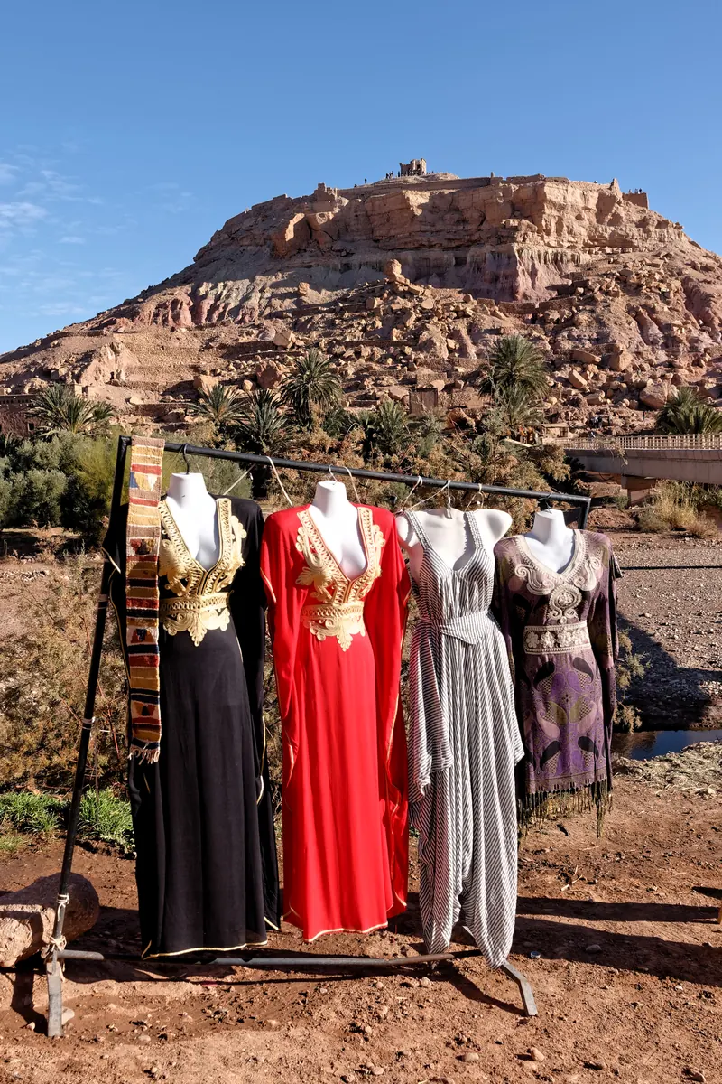 Garments on display in front of the earthen hill of Aït Benhaddou.