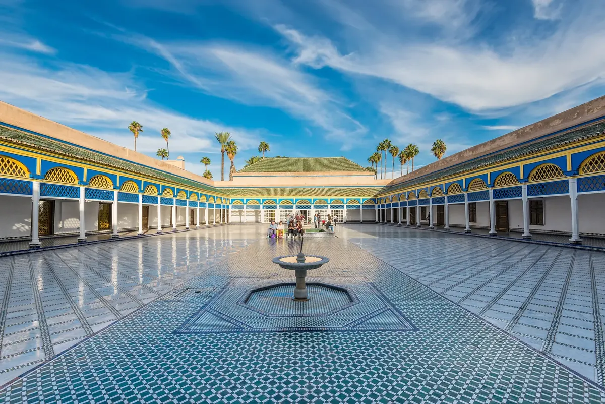 The broad tiled central courtyard and fountain at Bahia Palace, with blue-and-yellow arcades around the perimeter.