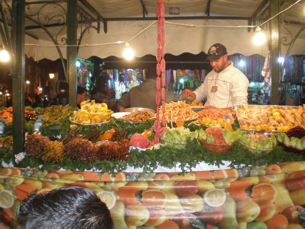 A food stall at Place Djemaa el-Fna in Marrakech, displaying fruit and snacks at night.