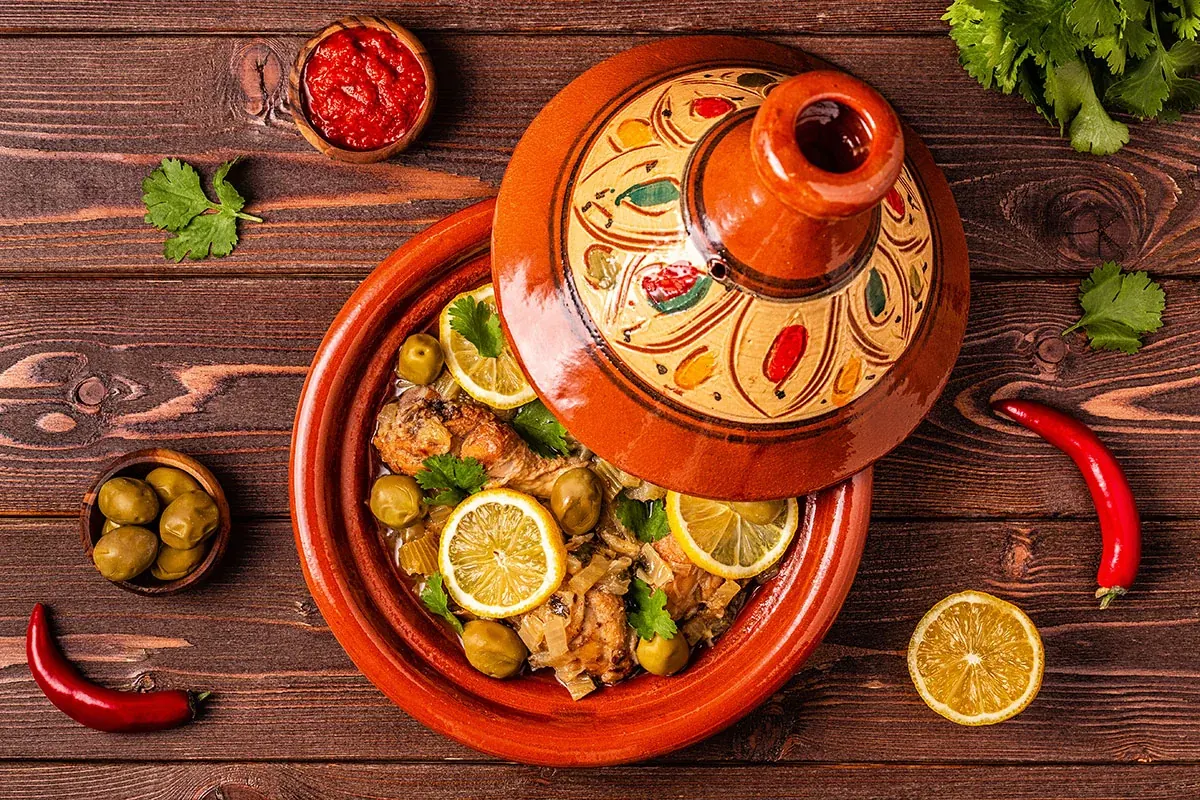 A Moroccan chicken tagine with vegetables and lemon, served in a decorated earthenware dish.