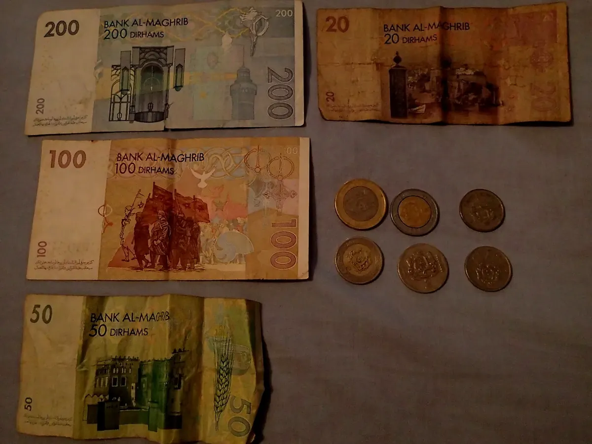 A photographed arrangement of Moroccan dirham banknotes and coins on a neutral surface.