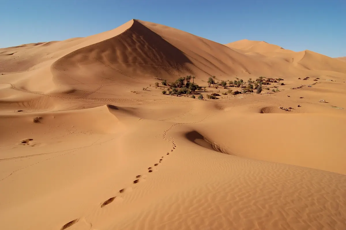 Sand dunes and a settlement among the Erg Chebbi dunes in Morocco
