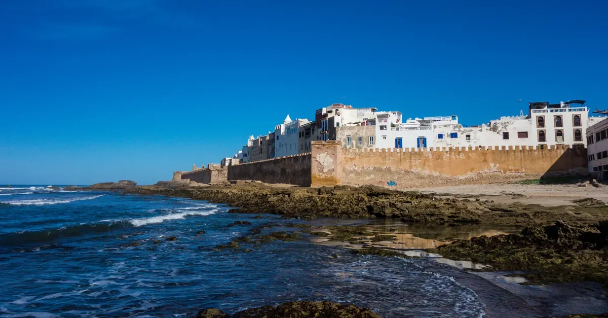 Whitewashed buildings of Essaouira’s fortified seafront beside the Atlantic Ocean and rocky shoreline.