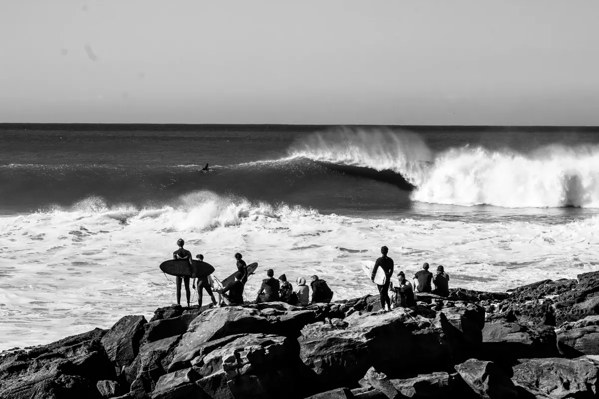 Surfers watch Atlantic waves from Taghazout beach, Morocco.