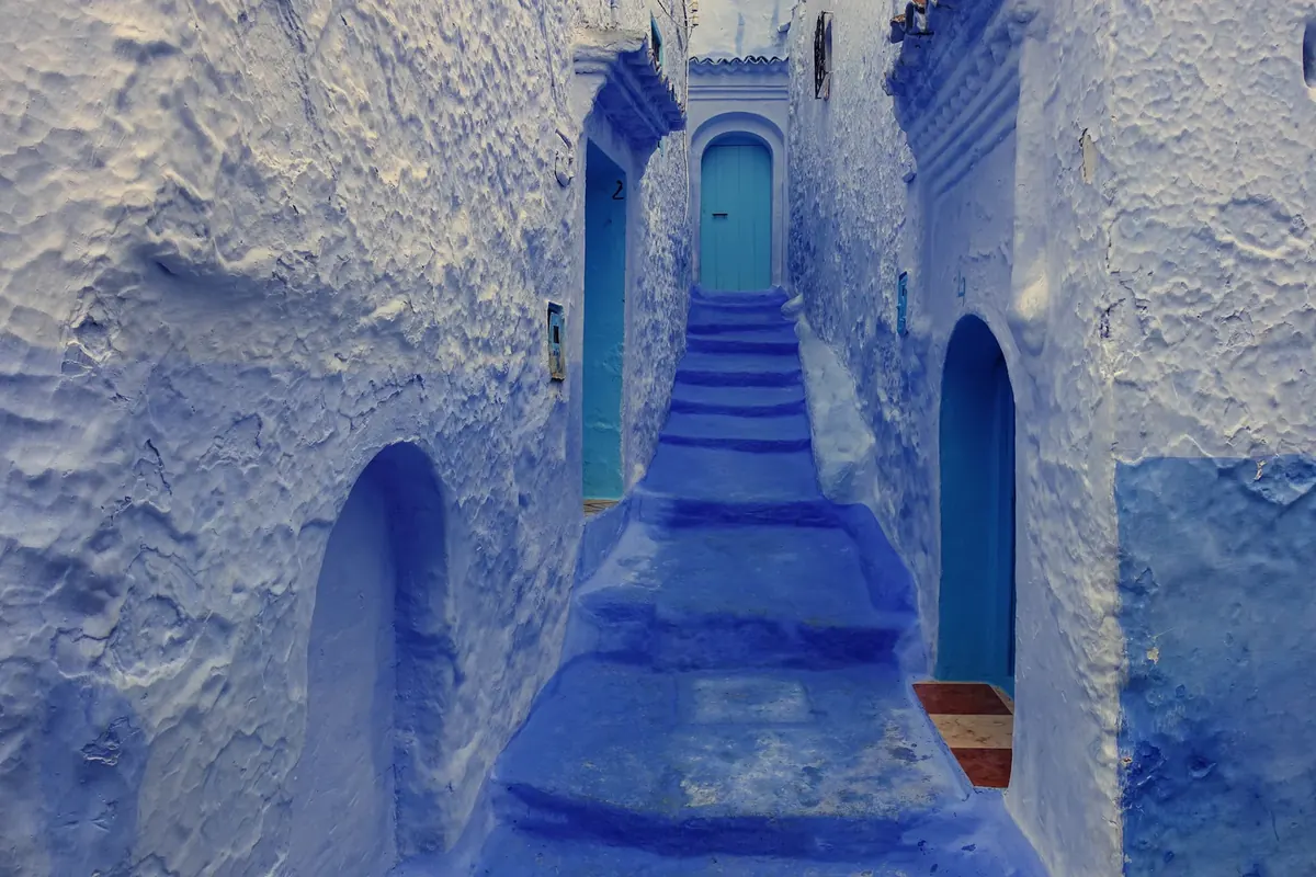 Blue-painted alleyway and traditional houses in Chefchaouen, Morocco.