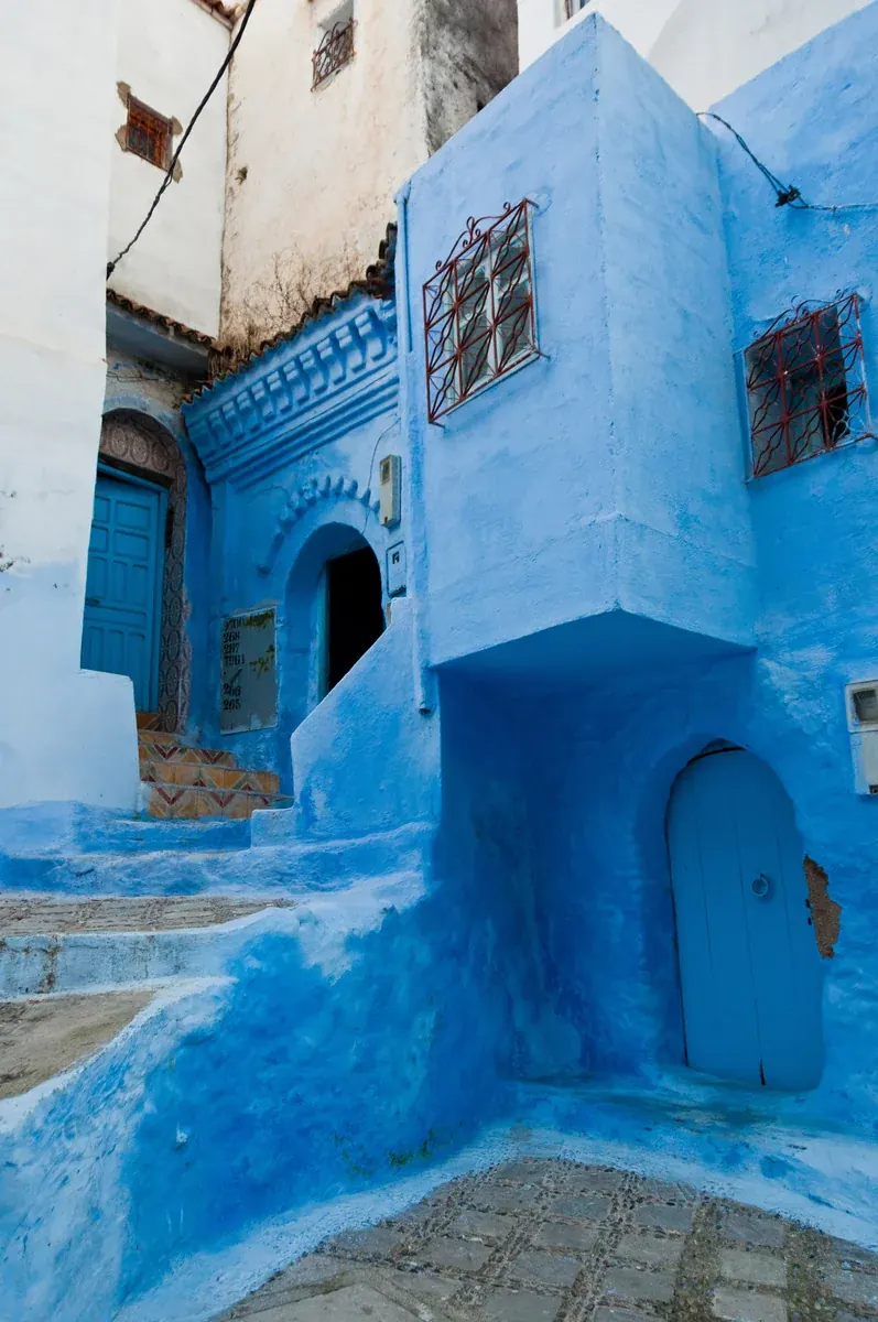 A blue-painted, stepped lane between closely spaced homes in Chefchaouen’s medina.