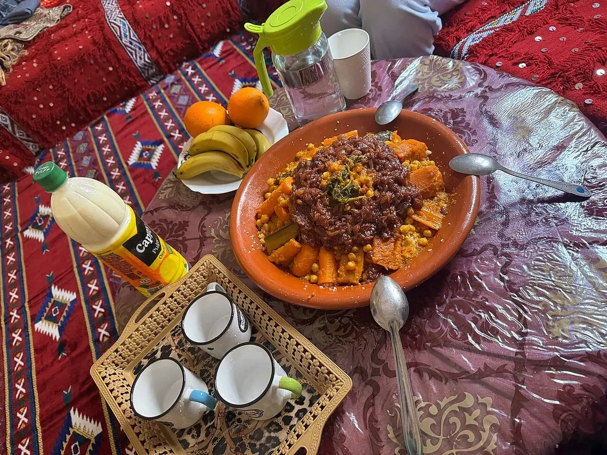 A Moroccan couscous platter arranged with vegetables and served with small bowls of accompaniments.