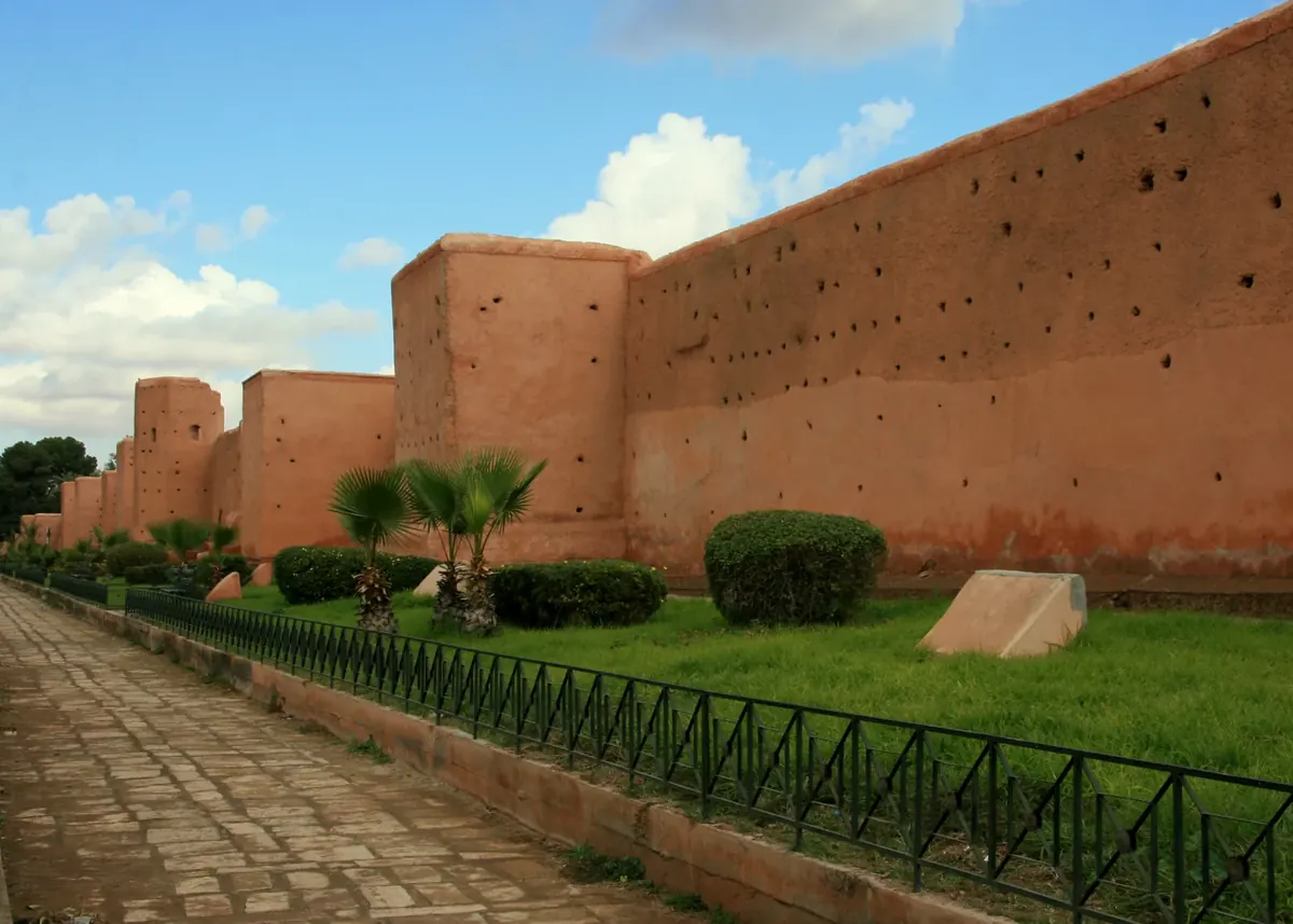 Ochre fortified wall of Marrakech’s historic Medina beneath a blue sky.