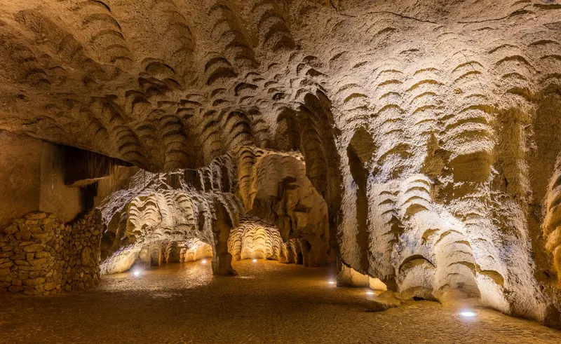 Lit interior of the Caves of Hercules in Tangier with curved quarry marks in the rock walls
