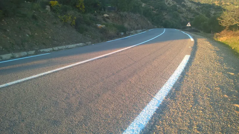 Curving paved national road with a bend warning sign in Chefchaouen, Morocco