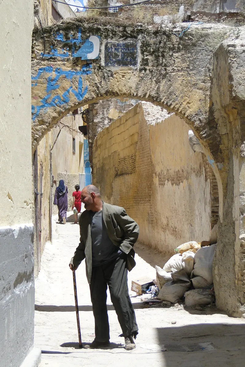 A pedestrian street beneath a weathered arch in the Medina of Meknes, photographed in 2010