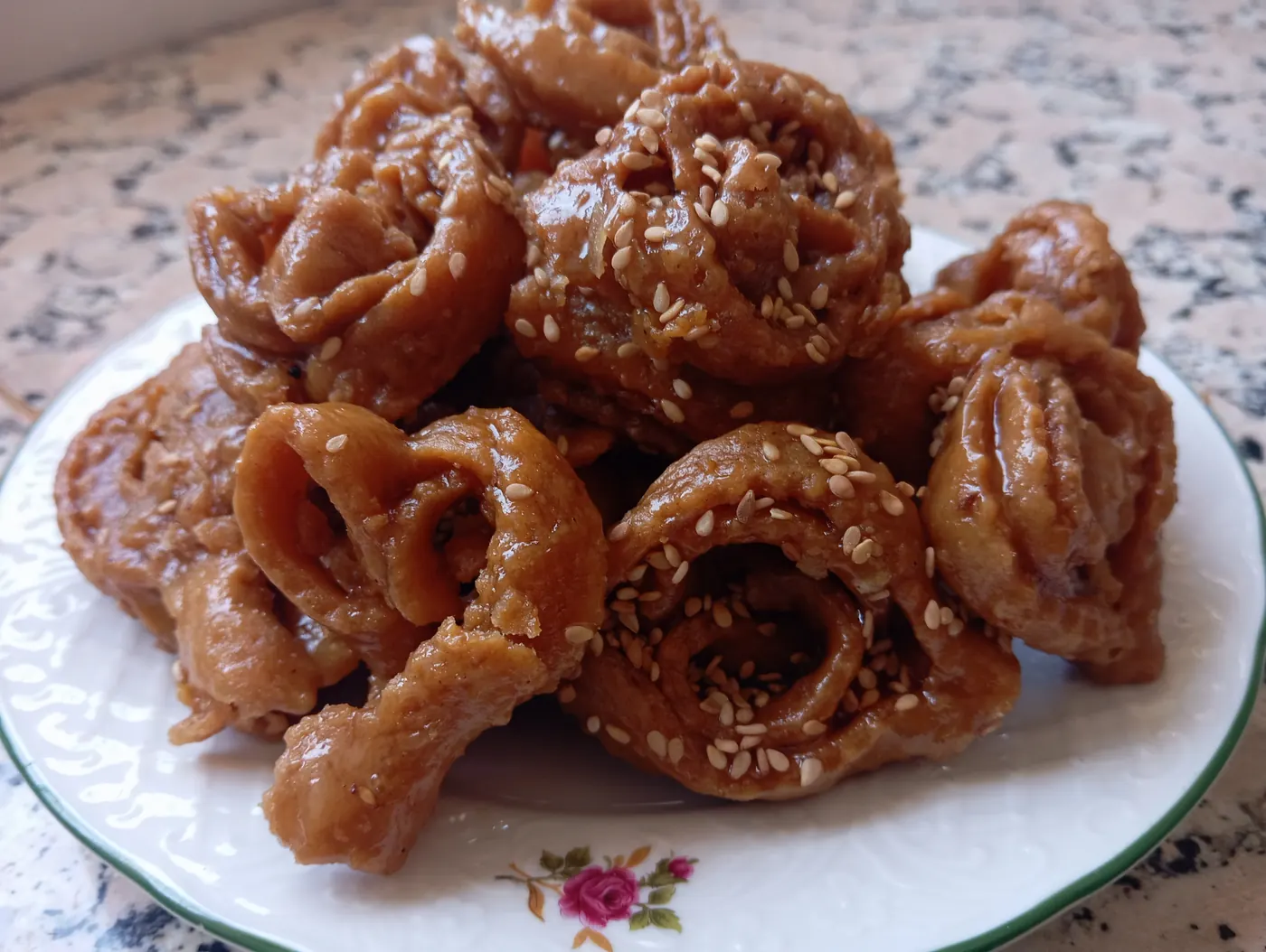 Close-up plate of honey-glazed, sesame-sprinkled Moroccan chebakia pastries