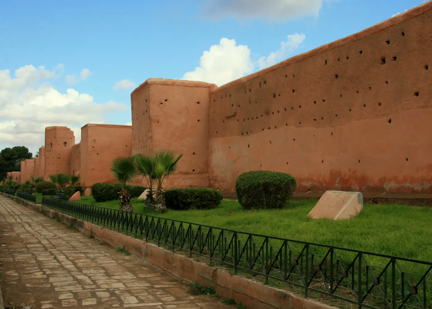 Marrakech old city wall and palm-lined path under a blue sky