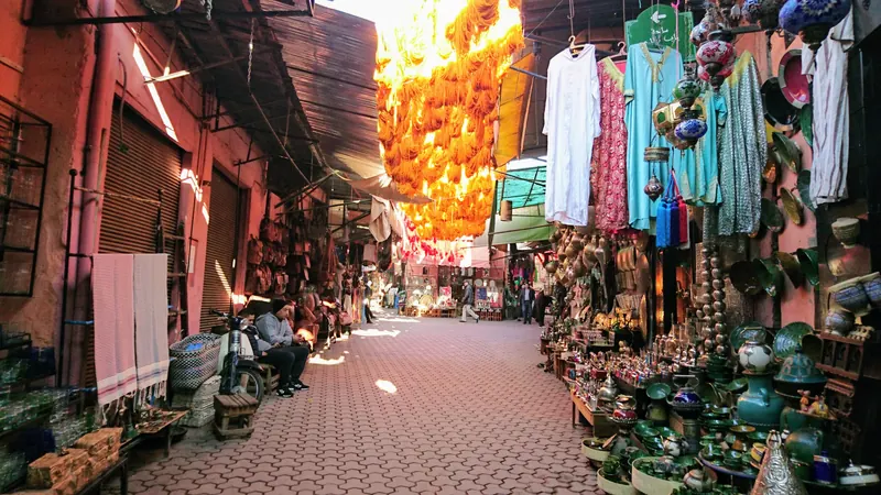 A street in the medina of Marrakech, Morocco, with ochre walls and shopfronts.