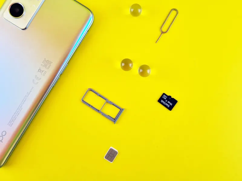 A generic smartphone with a SIM card, SIM tray and memory card on a yellow surface; not photographed in Morocco.