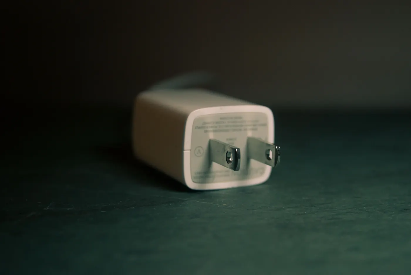 White wall charger plug lying on a dark surface