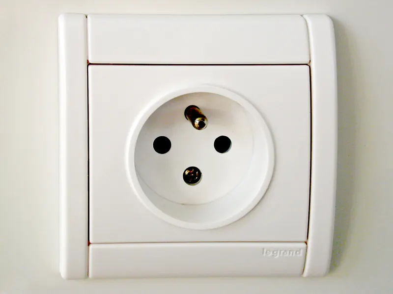 Close-up of a Type E wall socket with its round protruding earth pin