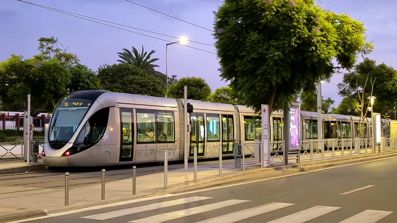 A Rabat-Salé tram stopped at a street-side platform at dusk.