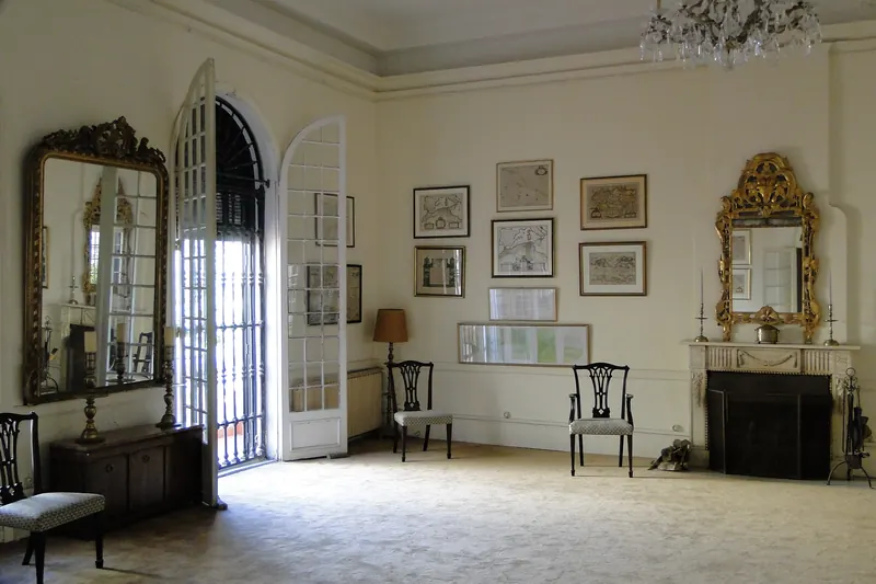 Historic reception room at the Tangier American Legation with framed maps, mirrors and a fireplace