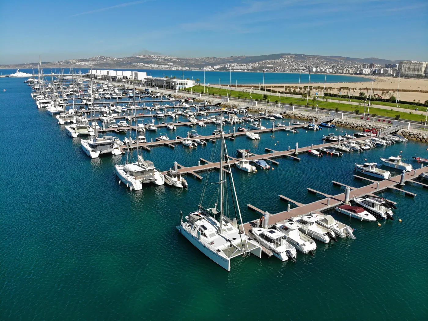 Aerial view of boats in Tanja Marina Bay, Tangier, with the city beach and waterfront behind.