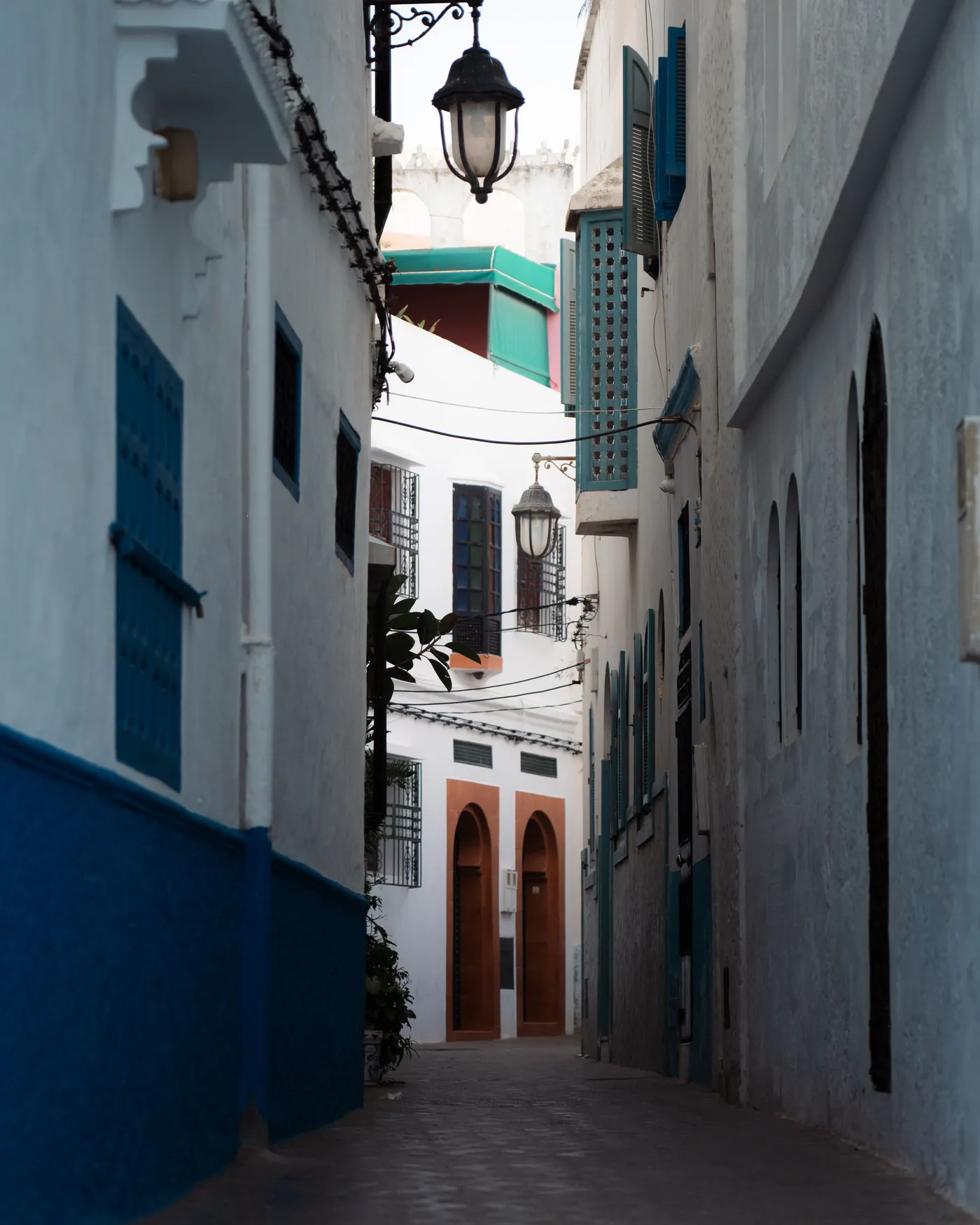 Narrow white-and-blue lane with hanging lamps in Asilah's medina