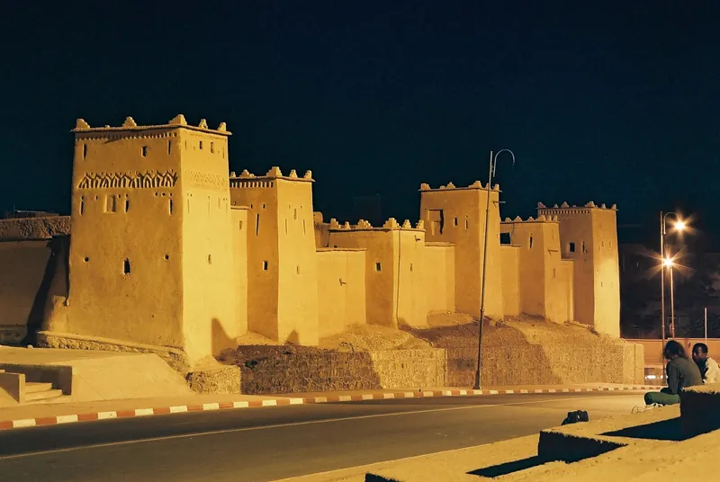 Kasbah Taourirt in Ouarzazate lit at night beside a road