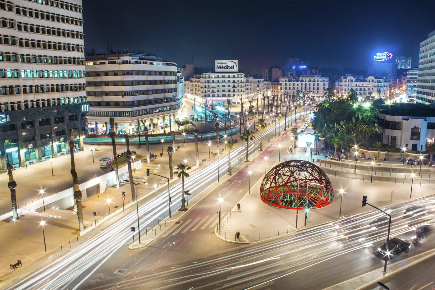 Nighttime view across Place des Nations Unies in central Casablanca, with traffic light trails.