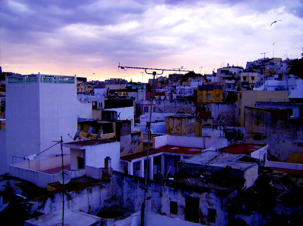 White rooftops across Tangier's Medina beneath a clouded evening sky.